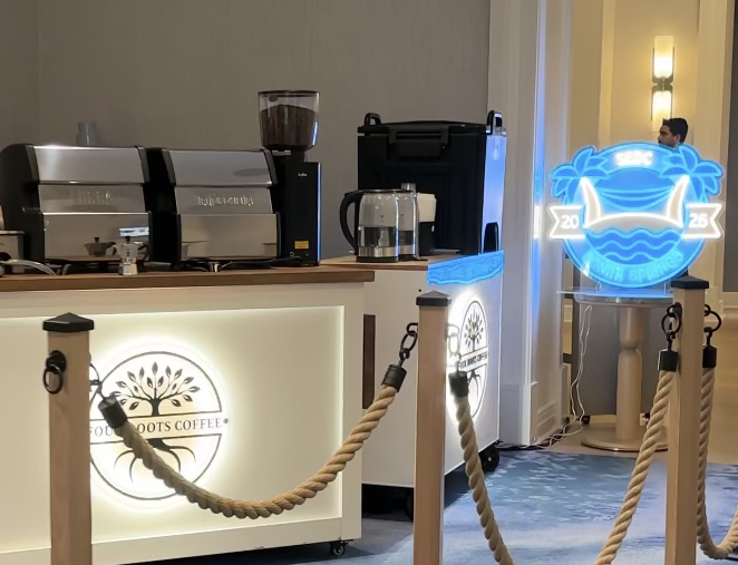 Four Roots Coffee carts with an illuminated custom event sign at a corporate hotel event